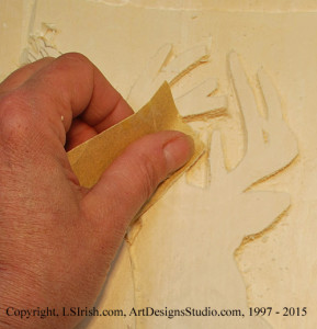 Using sandpaper on a relief wood carving
